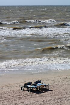 Two empty plastic deck chairs on the background of sea waves on a summer afternoon