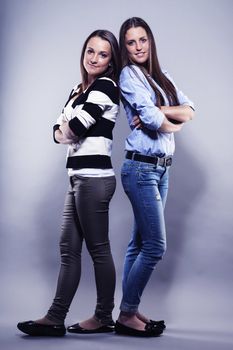 two teenager standing back to back on gray background