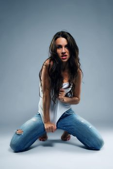 wild beautiful woman wearing blue jeans kneeling on the floor