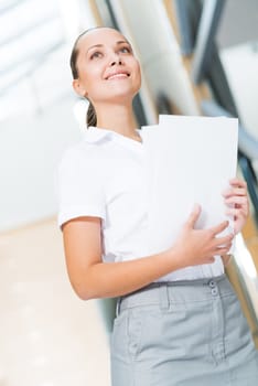 Portrait of a successful business woman in the office, holding papers and smile