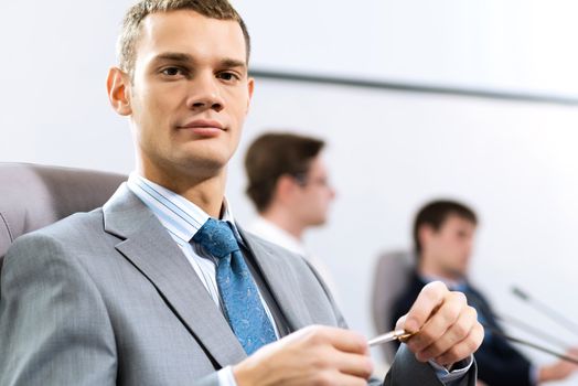 Portrait of a businessman sitting at a table and holding a pen