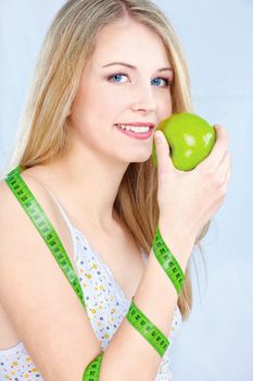 Pretty blond girl with apple and measuring tape