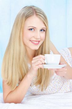 Pretty blond woman drinking coffee in bed