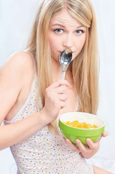 Young blond woman holding spoon and corn flakes