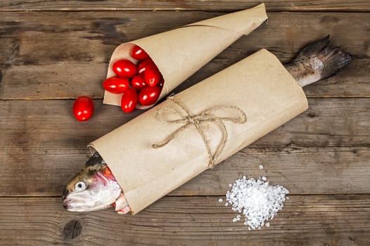 Fresh salmon in the paper-bag with salt and tomato