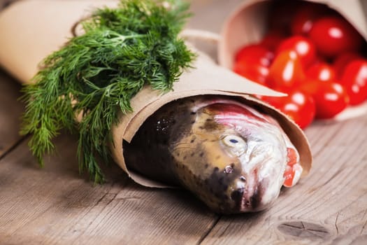 Fresh salmon in the paper with a pice of greenery and some small tomatoes