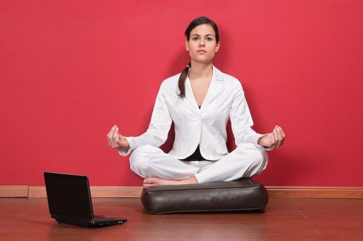 Young businesswoman sitting in yoga lotus position with laptop on the floor