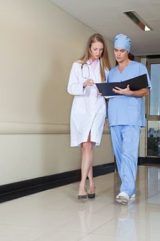 Doctor and nurse reading file while walking in hospital