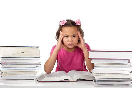 A young girl holds her head in a frown at a desk covered with many big books.