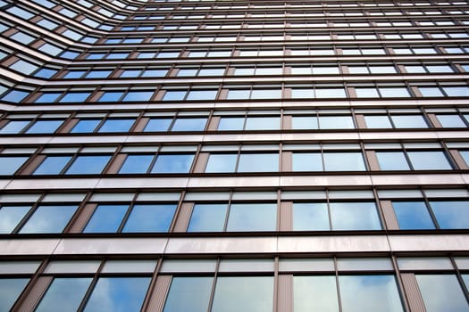 facade of office building with regular pattern windows reflecting white cloud