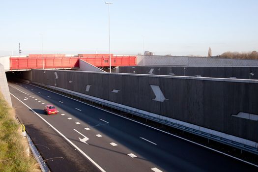 red car leaves tunnel over motorway A2 in The Netherlands
