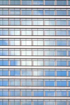 facade of office building with windows reflecting white cloud