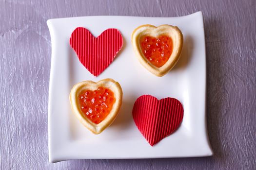 Tartlets with red caviar and paper hearts on Valentine's Day