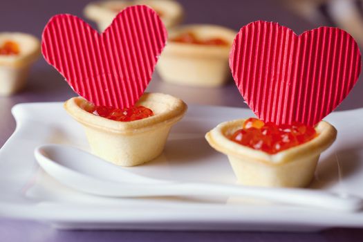 Tartlets with red caviar and paper hearts on Valentine's Day