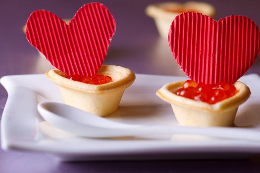 Tartlets with red caviar and paper hearts on Valentine's Day