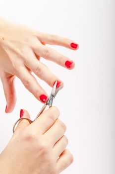 An image of female red nails and scissors