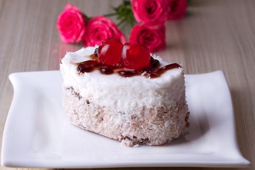 Celebratory cake with cherries on a background of pink roses