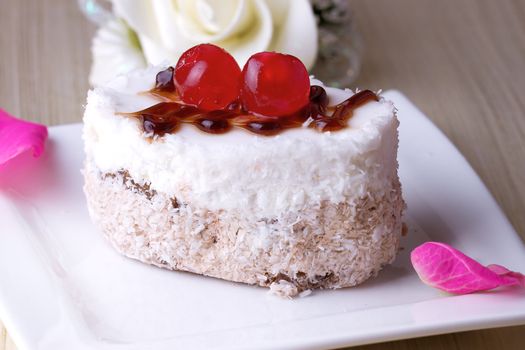 Celebratory cake with cherries on a background of pink roses