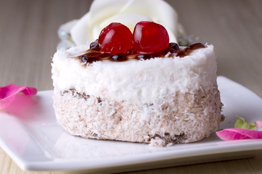 Celebratory cake with cherries on a background of pink roses