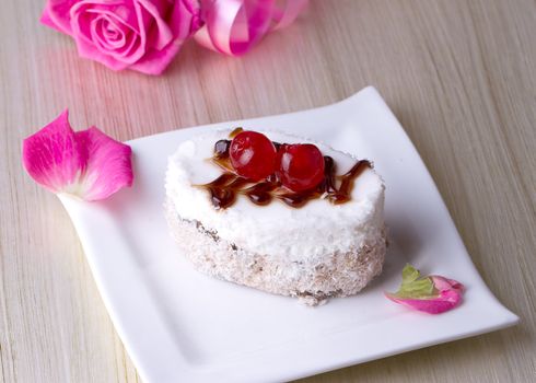 Celebratory cake with cherries on a background of pink roses