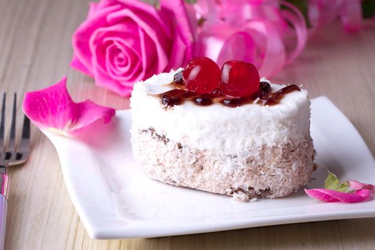 Celebratory cake with cherries on a background of pink roses