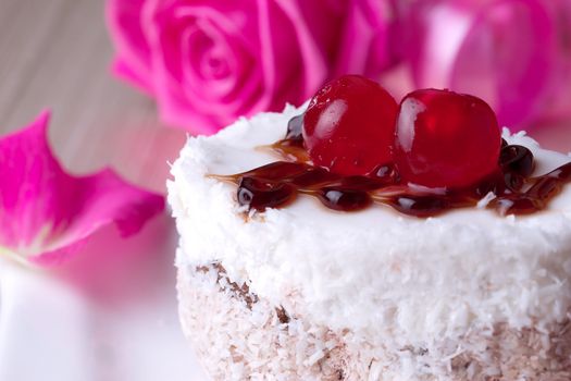 Celebratory cake with cherries on a background of pink roses