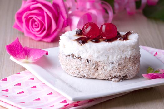 Celebratory cake with cherries on a background of pink roses