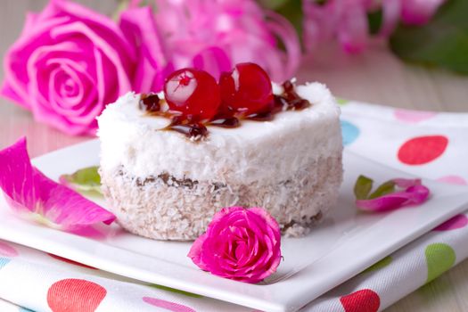 Celebratory cake with cherries on a background of pink roses