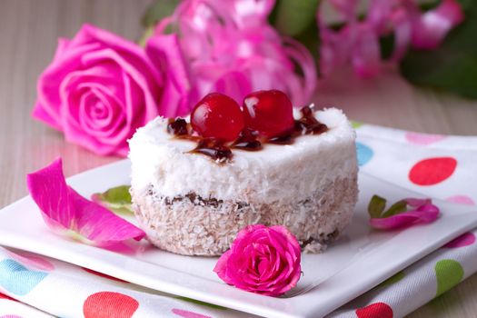 Celebratory cake with cherries on a background of pink roses