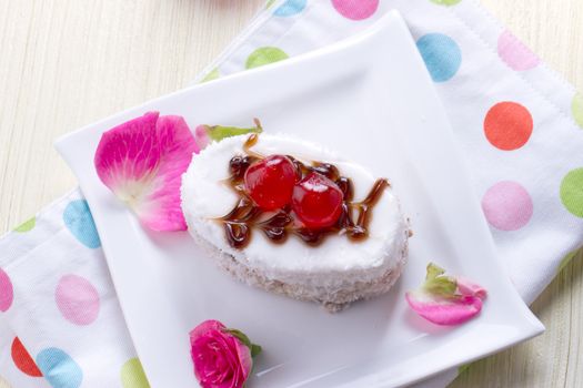 Celebratory cake with cherries on a background of pink roses