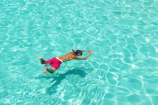 Man snorkeling in crystal clear turquoise water at tropical beach