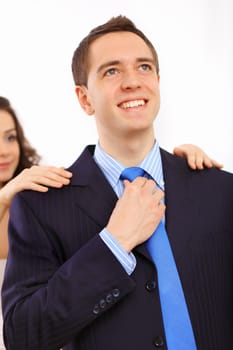 Young businessman dressing at home in the morning. Woman helping to fasten his tie