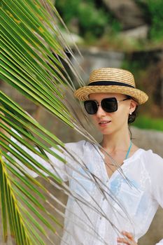 Woman in sunglasses near palm tree wearing hat