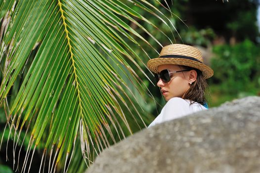 Woman in sunglasses near palm tree wearing hat