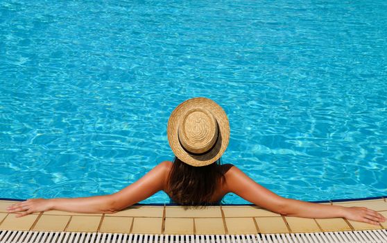 Woman in hat relaxing at the pool 