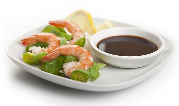 Three boiled shrimp's tails with leek, lettuce, lemon and soy sausage on the white plate