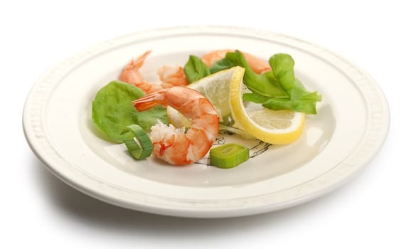 Three shrimp's tails with leek, lettuce and lemon on the white plate