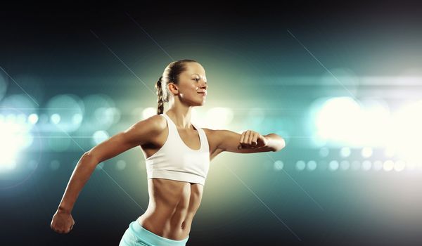 Fitness woman standing against color lights background
