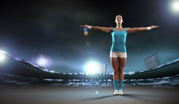 Image of sportswoman exercising against stadium lights background