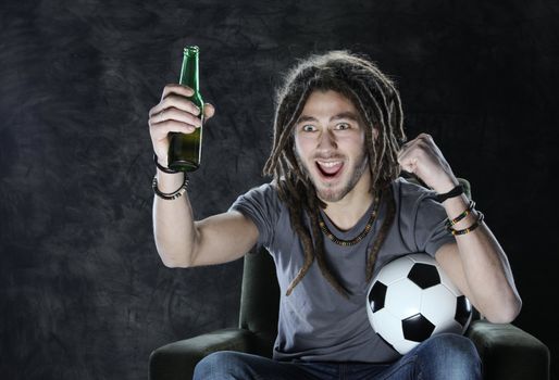Young adult man exults watching football on television: Goal!