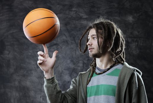 Portrait of young man spinning basketball on finger