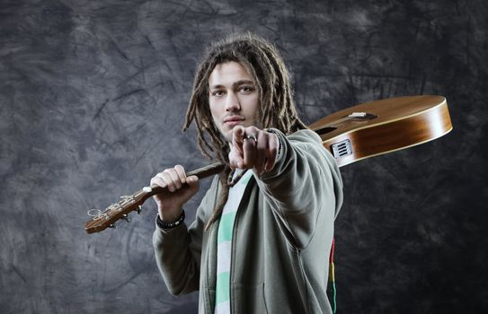 Young man with his guitars pointing at viewer