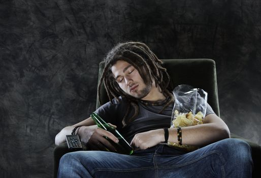 A man sleeps on the couch with beer and chips