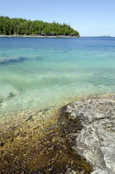 Green and blue water of Huron Lake, Ontario under blue sky.