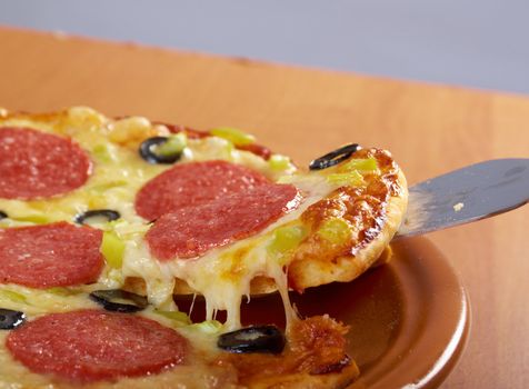 taking slice of pizza,melted cheese dripping.Pepperoni