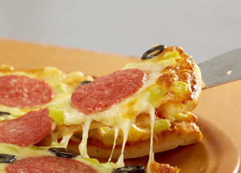 taking slice of pizza,melted cheese dripping.Pepperoni