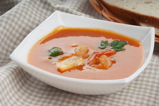 Tomato soup with shrimps and parsley in the white bowl