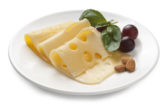 Assorted pieces of cheese with basil, almond and grape on the white plate