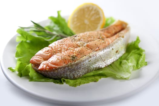 Fried trout with lettuce and lemon on the plate