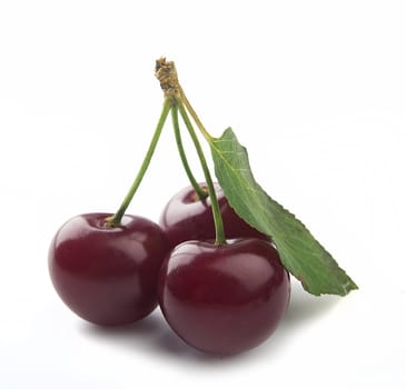 Three cherries with green leaf on the white